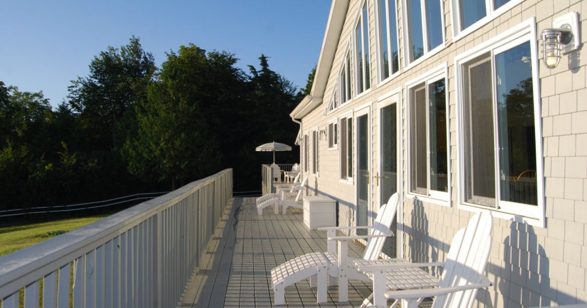 Deck of a luxury vacation rental with white Adirondack chairs.