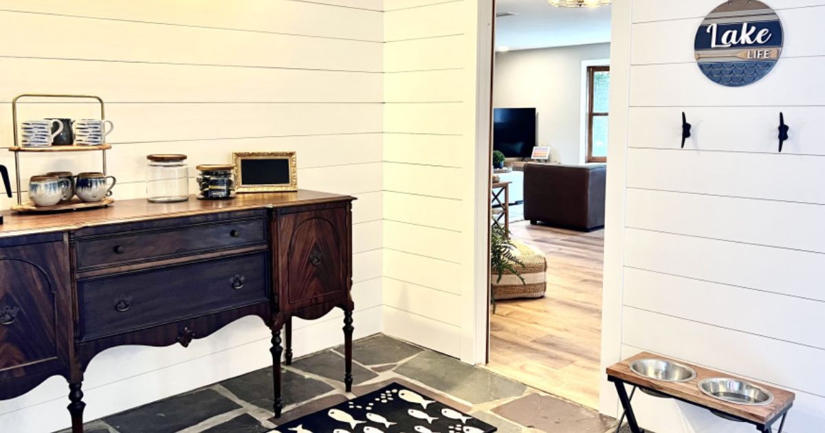 Tastefully designed interior entry of a lake house with white shiplap walls, and an antique console table.