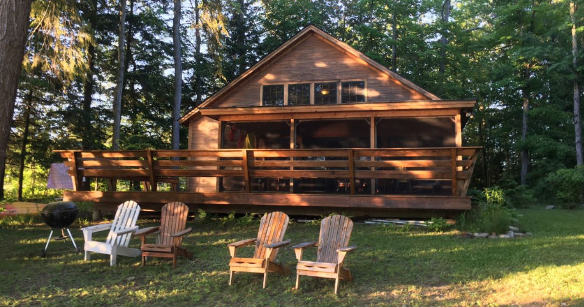 Two cottages side by side on the lake, with a beach and dock.